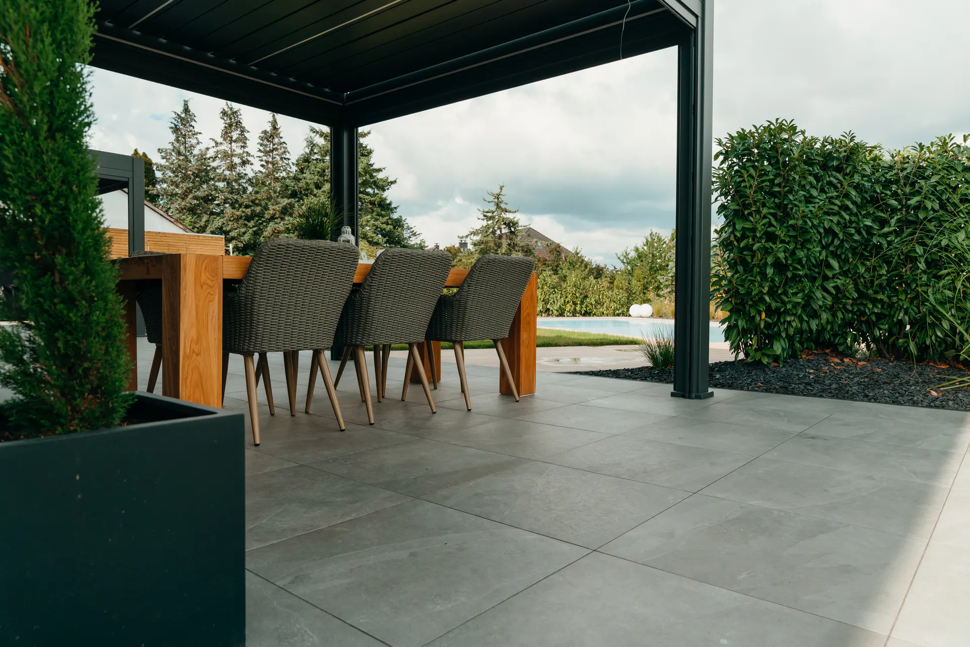 Überdachte Terrasse mit großformatigen Platten und Blick in den Garten